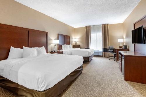 a hotel room with two beds and a flat screen tv at Comfort Inn Louisville Southwest in Louisville