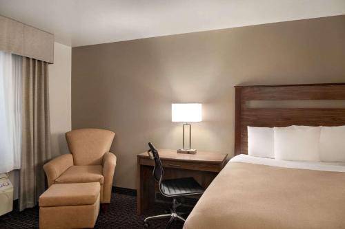 a hotel room with a bed and a chair and a desk at Baymont by Wyndham Buffalo in Buffalo