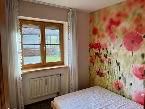 a bedroom with a bed and a window with flowers on the wall at Allgäu-Moni Trauchgau in Halblech