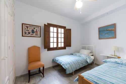1 Schlafzimmer mit 2 Betten, einem Stuhl und einem Fenster in der Unterkunft Veoapartment San Marcos in Sevilla