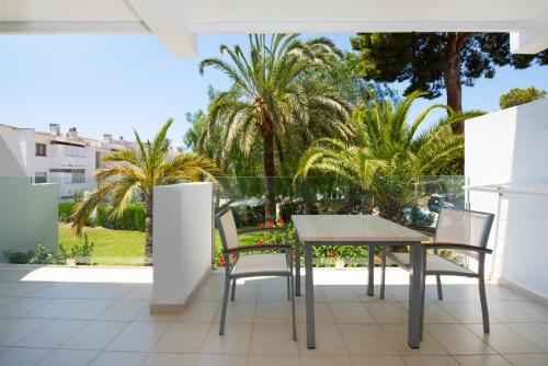 a table and chairs on a balcony with palm trees at Aparthotel Ponent Mar in Palmanova