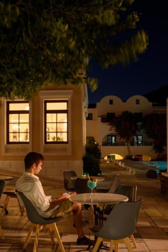 a man sitting in a chair at a table at night at Veggera Beach Hotel in Perissa