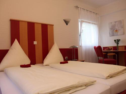 a bedroom with two beds and a desk and a window at Hotel Villa Casa in Düsseldorf