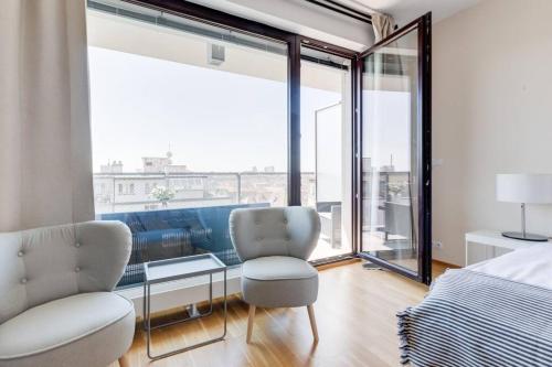 sypialnia z łóżkiem i krzesłem oraz dużymi oknami w obiekcie JT's Apartments Korunní str. w Pradze