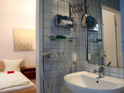 a bathroom with a sink and a mirror and a bed at Hotel Villa Casa in Düsseldorf