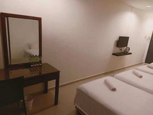 a room with two beds and a mirror and a desk at T Hotel Anggerik in Alor Setar