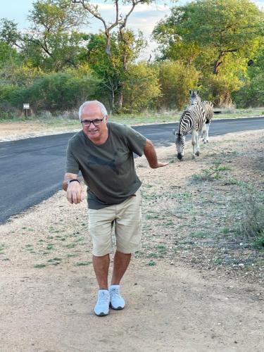 an older man standing on the side of a road with a zebra at Lindiwe Safari Lodge in Hoedspruit