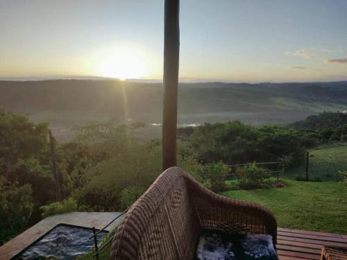 a wicker chair sitting on a table with the sunset at African Sunset Villa in Chintsa