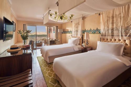 a hotel room with two beds and a balcony at Sofitel Legend Old Cataract in Aswan