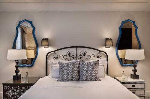 a bedroom with a bed with two lamps and two mirrors at Orient by Isrotel Exclusive in Jerusalem