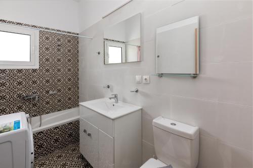 a white bathroom with a toilet and a sink at Paradise Garden in Kolimbia