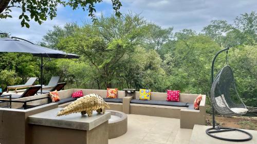 a patio with couches and an umbrella and an animal statue at Lindiwe Safari Lodge in Hoedspruit