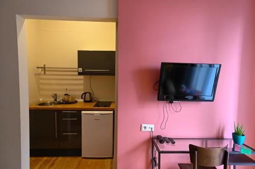 a kitchen with a pink wall with a tv on the wall at No11 Hotel & Apartments in Istanbul