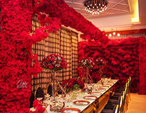 a long table with red flowers on a wall at Base Ethiopia International Hotel in Addis Ababa