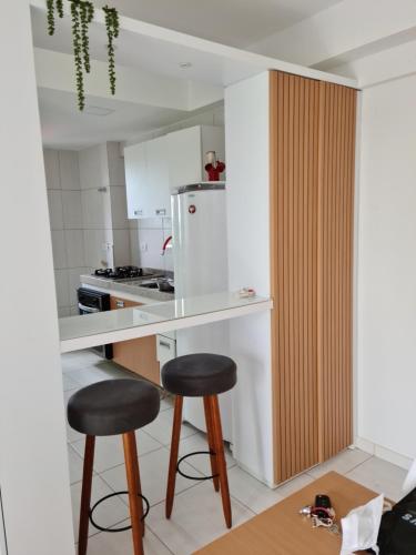 a kitchen with two bar stools and a white refrigerator at Flat próximo à UFPE in Recife