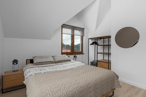 a white bedroom with a bed and a window at Tylko Tu i Teraz- Sauna, Balia z jacuzzi, Bon turystyczny in Baligród