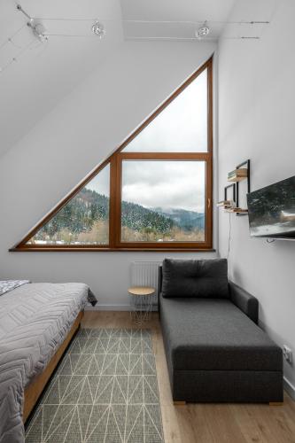 a bedroom with a bed and a couch and a window at Tylko Tu i Teraz- Sauna, Balia z jacuzzi, Bon turystyczny in Baligród