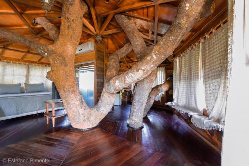 a tree in the middle of a room with a wooden ceiling at Lendas do Capão Pousada in Vale do Capao