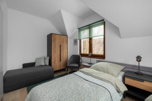 a bedroom with a bed and a chair and a window at Tylko Tu i Teraz- Sauna, Balia z jacuzzi, Bon turystyczny in Baligród