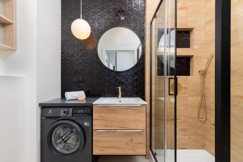a bathroom with a washing machine and a mirror at Ostoya Pucka Apartament by Noclegi Renters in Puck