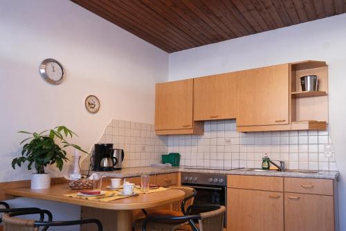 a kitchen with wooden cabinets and a table with a clock on the wall at Ferienwohnungen Berger in Kötschach