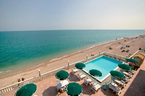a view of a beach with a swimming pool and green umbrellas at Hotel Brigantino Non Dista in Porto Recanati