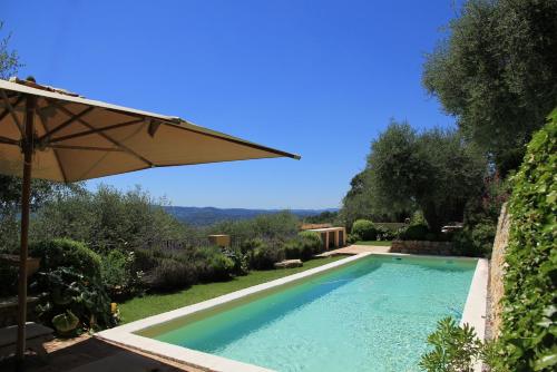 une piscine dans une cour avec un parasol dans l'établissement Villa La Lavande, à Valbonne