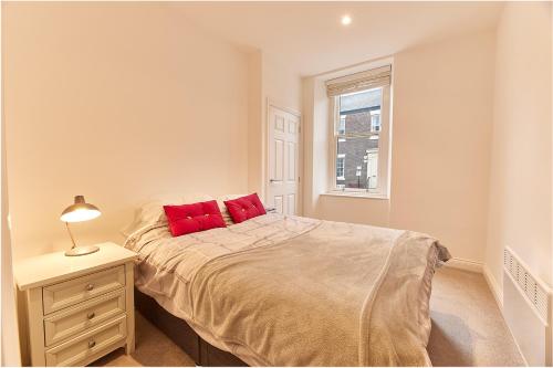 um quarto com uma cama com almofadas vermelhas e uma janela em Penshaw Boutique Apartment em Sunderland