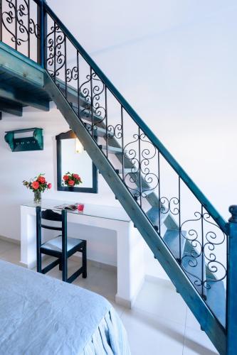 a bedroom with a staircase with a table and a chair at Veggera Beach Hotel in Perissa