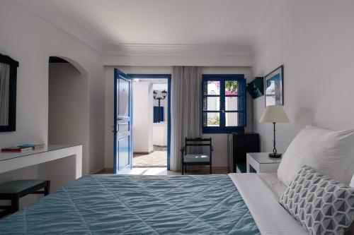 a bedroom with a bed and a door to a room at Veggera Beach Hotel in Perissa