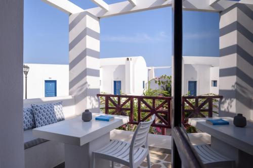 a patio with two tables and chairs on a balcony at Veggera Beach Hotel in Perissa