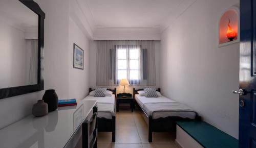 a room with three beds and a window at Veggera Beach Hotel in Perissa