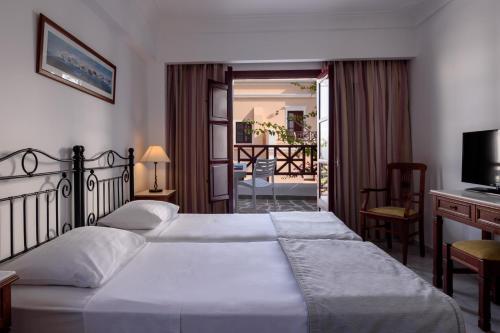 a hotel room with two beds and a balcony at Veggera Beach Hotel in Perissa
