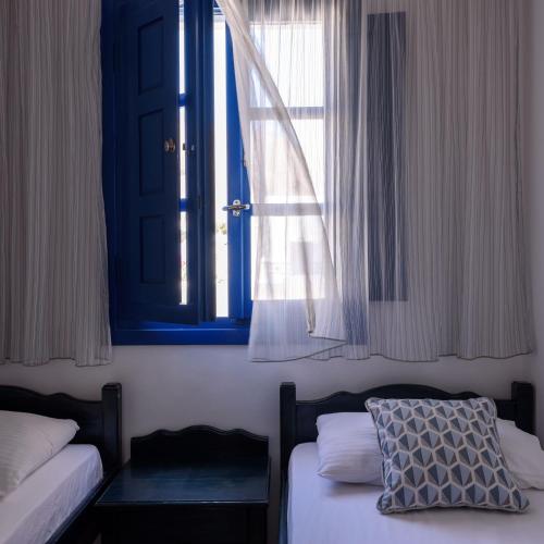 a bedroom with two beds and a window at Veggera Beach Hotel in Perissa