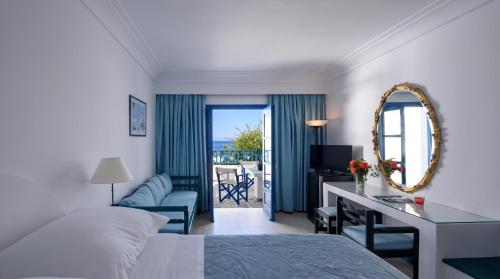a bedroom with a bed and a desk with a mirror at Veggera Beach Hotel in Perissa