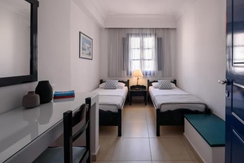a room with two beds and a table and a window at Veggera Beach Hotel in Perissa