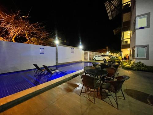a patio with chairs and a swimming pool at night at Solar Porto Rico in Porto De Galinhas