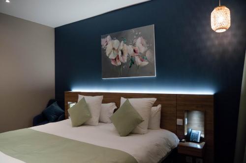 a bedroom with a bed with a blue wall at Hôtel & Restaurant La maison des blés in Boutervilliers