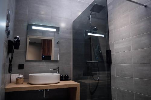 a bathroom with a sink and a shower at Logis- Hôtel & Restaurant La maison des blés in Boutervilliers