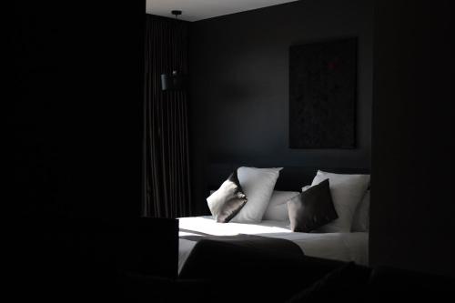 a bedroom with a white bed with pillows on it at Hôtel & Restaurant La maison des blés in Boutervilliers