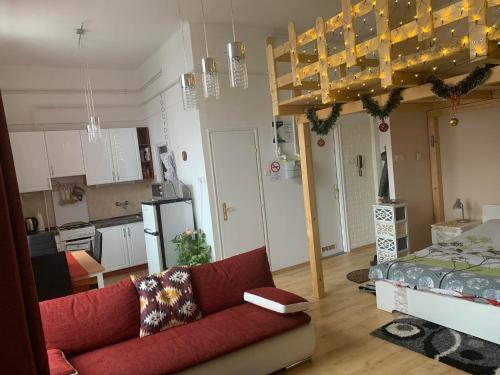 a living room with a red couch and a kitchen at Város szíve apartman in Kaposvár