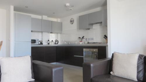 a kitchen with black and white cabinets and two chairs at Citystay Living - The Vie in Cambridge