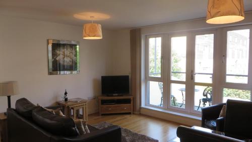a living room with two couches and a television and windows at Citystay Living - The Vie in Cambridge