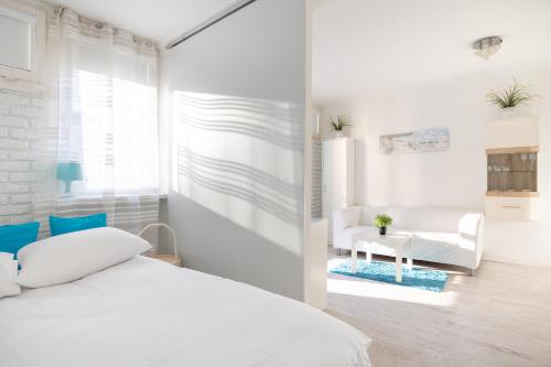 biała sypialnia z łóżkiem i krzesłem w obiekcie Rondo ONZ Business Apartment w Warszawie