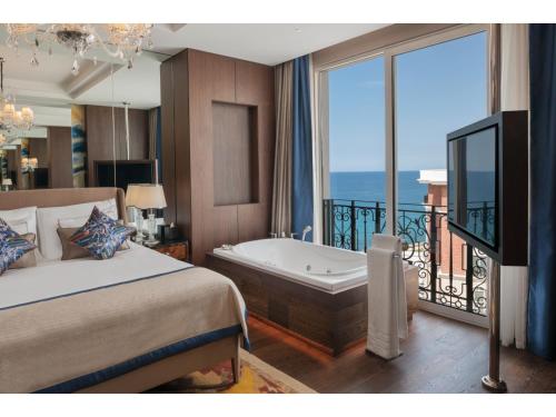 a bedroom with a bed and a tub and a balcony at Kaya Palazzo Resort & Casino in Kérynia
