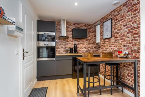 a kitchen with a brick wall and a table at Location d'appartements - Cosysejour - Calme Fibre Netflix in Amiens