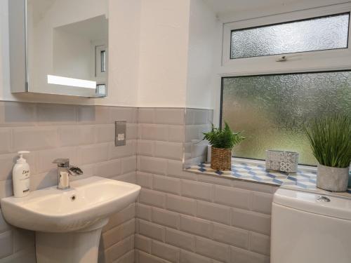 a white bathroom with a sink and a window at Green Stile Cottage in Windermere