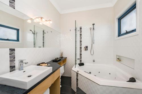 a white bathroom with a tub and a sink at Seascape Accommodation in Portland