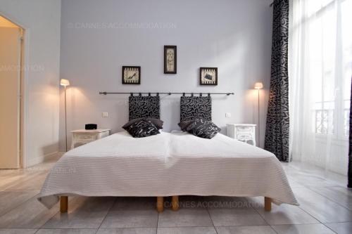 - une chambre blanche avec un grand lit et des oreillers noirs dans l'établissement Colombe, à Cannes