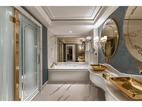 baño con bañera y espejo grande en Kaya Artemis Resort & Casino, en Vokolidha